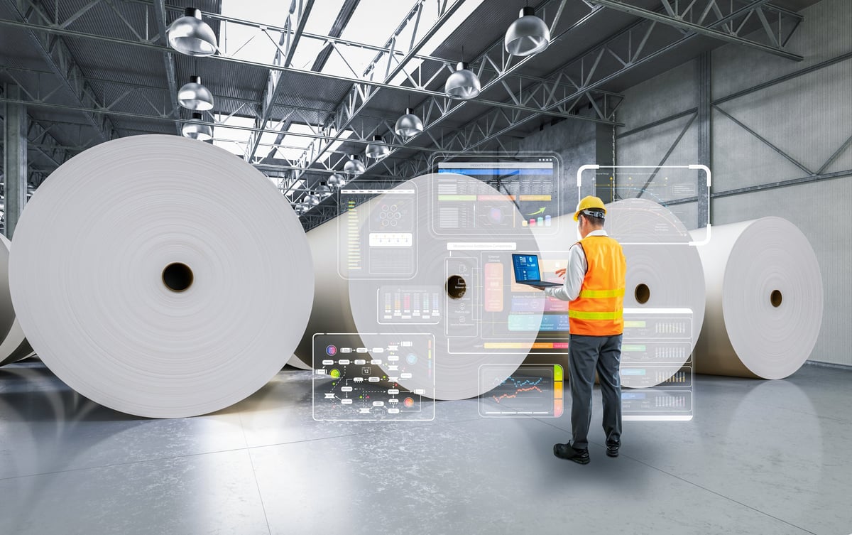Engineer working in a paper factory with computer and digital panel